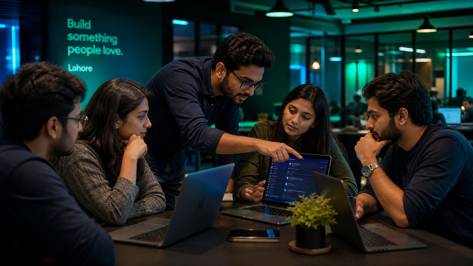 Small group of business owners in a Lahore workspace learning together around a laptop showing a chat interface